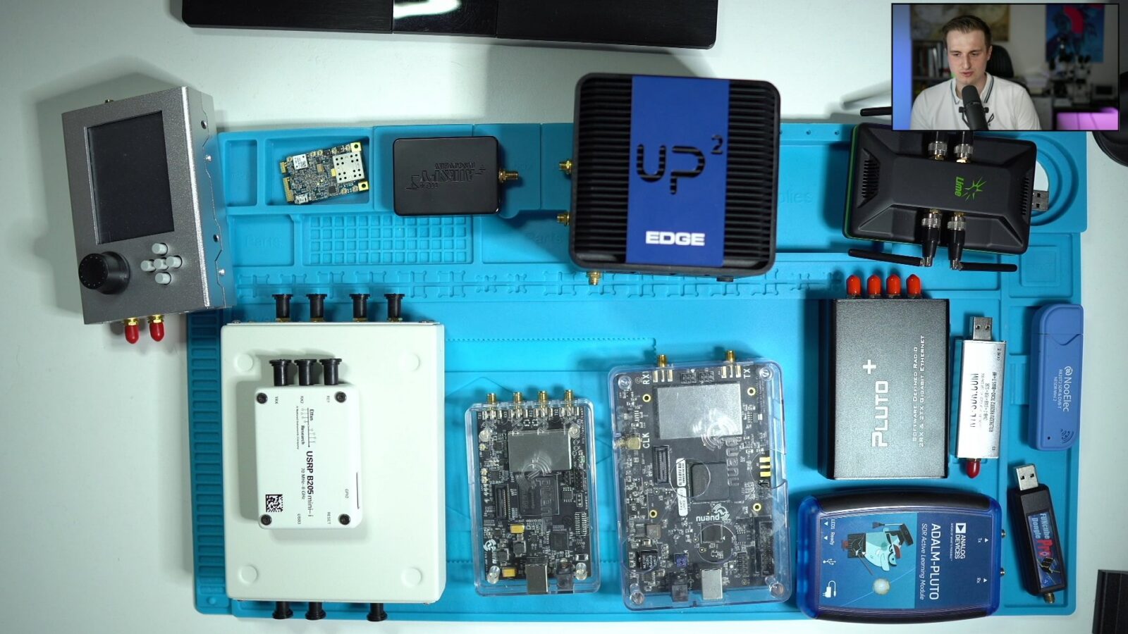 Course video frame: software-defined radios laid out on an ESD mat, with the trainer on webcam